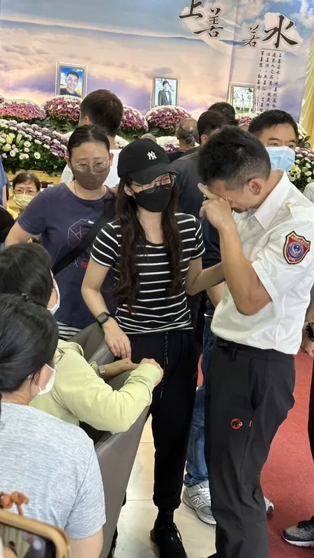 屏東縣消防局屏二分隊分隊長李炯佑（前右）24日赴靈堂，在殉職隊員施寶翔家屬旁難掩情緒痛哭，施寶翔遺孀（中條紋上衣者）從旁安慰，場面哀戚。（民眾提供）中央社