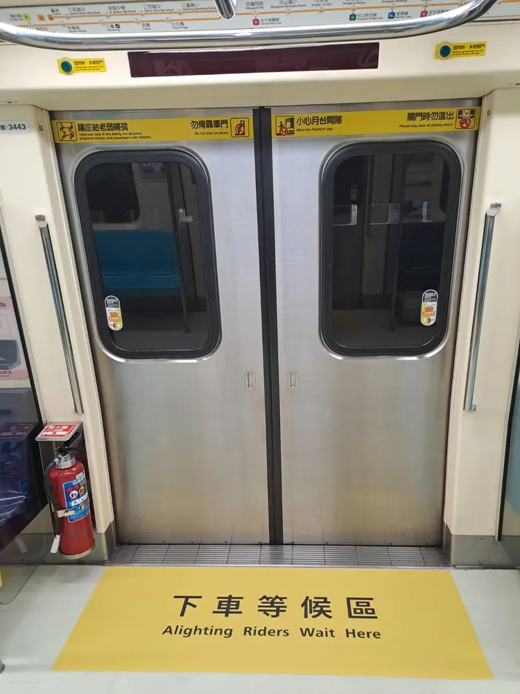 車廂頂部及地板分別張貼「請往車廂內部移動」、「下車等候區」宣導指標，分流上下車旅客。北捷提供