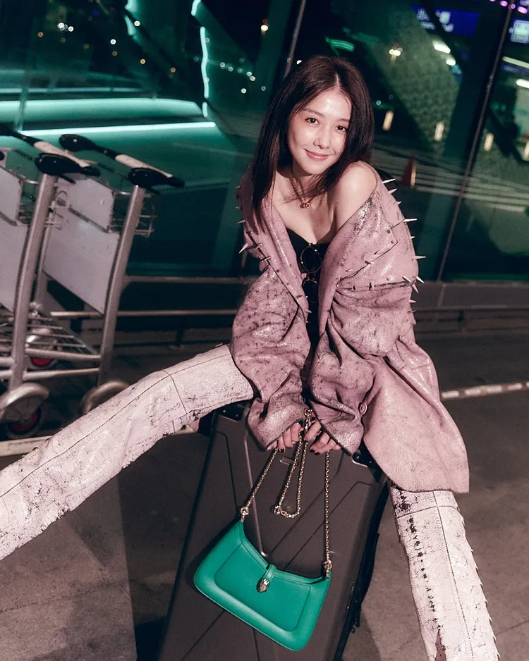 她俏皮坐在行李箱上小露香肩，自稱「有點迷人、有點小反派」。品牌提供