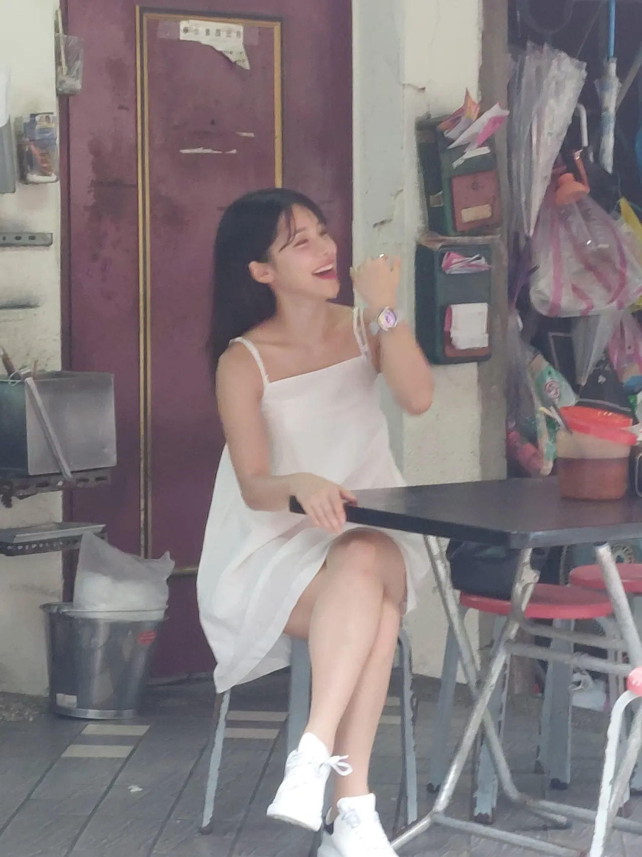 李多慧穿著白色洋裝坐在牛肉麵店,一臉笑容的她看起來心情很好。翻攝自爆廢公社二館