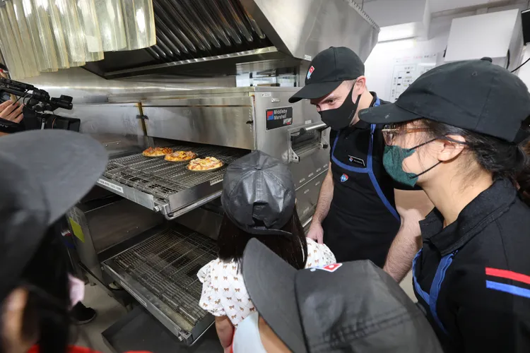 達美樂CEO與小朋友一起等待披薩出爐。業者提供