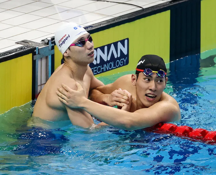 「台灣蝶王」王冠閎（左）29日晚間在杭州亞運游泳男子200公尺蝶式決賽中拿下銀牌，賽後在泳池中與
金牌得主本多燈（右）互相致意。中央社