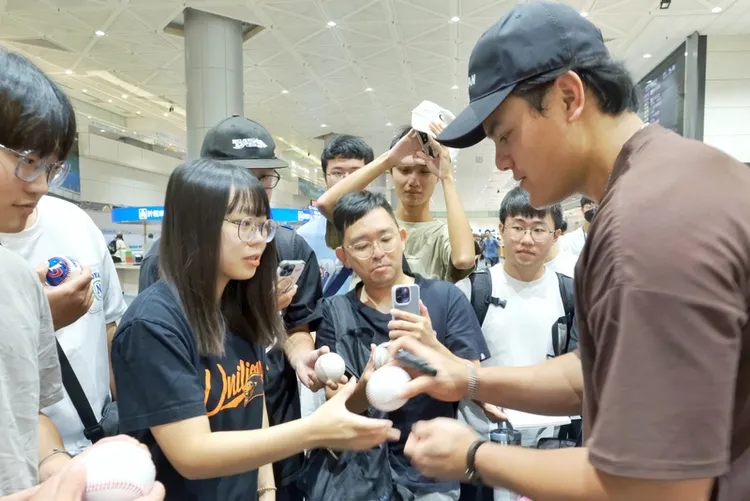 旅美棒球好手張育成（右）27日清晨搭機返台，吸引不少球迷到桃園國際機場接機，張育成也一一為球迷們簽名並合影。中央社