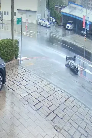 機車騎士疑似打滑，人被拋摔落地，騎士和機車宛如坐在「滑水道」上在馬路上往前衝。翻攝自汐止集團