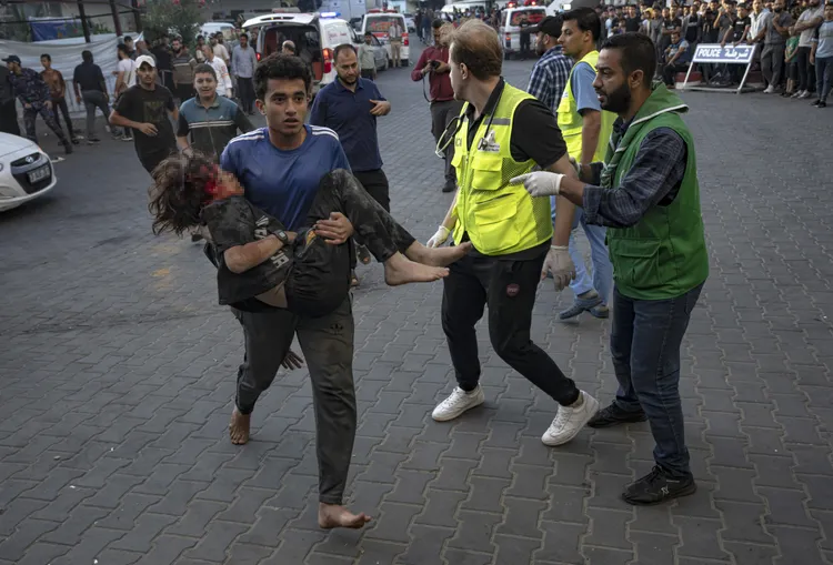 哥哥光腳抱著受傷的弟弟，送往醫院。美聯社