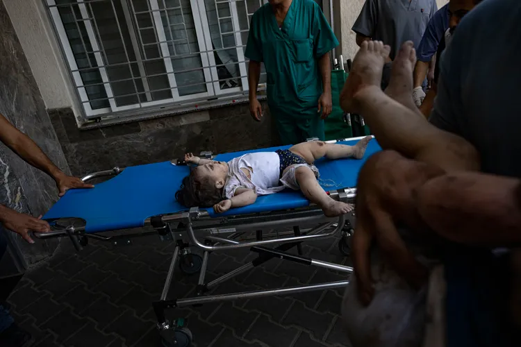 幼童從瓦礫中救出，送往醫院等待救治。美聯社