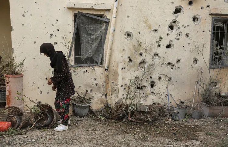 巴勒斯坦一名婦女在自家門外，她家牆上滿是彈孔。路透社
