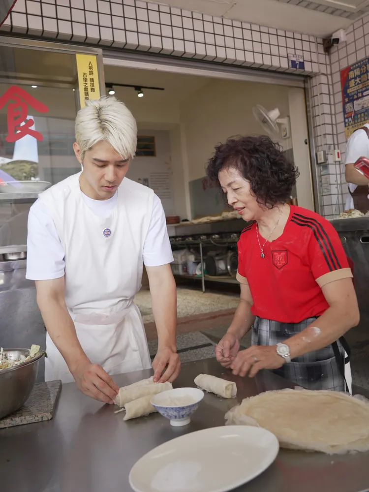 胡宇威（左）學習包潤餅。華視提供