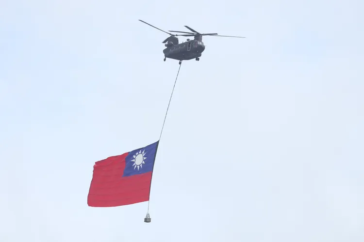 黑鷹直升機的護衛下，契努克運輸直升機吊掛巨幅國旗，飛越觀禮台。彭欣偉攝