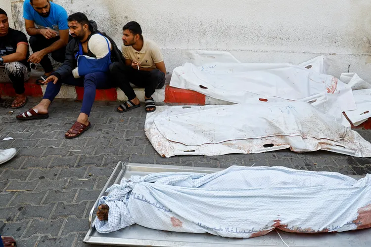 一名巴勒斯坦男子在以色列空襲中受傷，他懷孕的妻子躺在一旁、蓋上白布。路透社