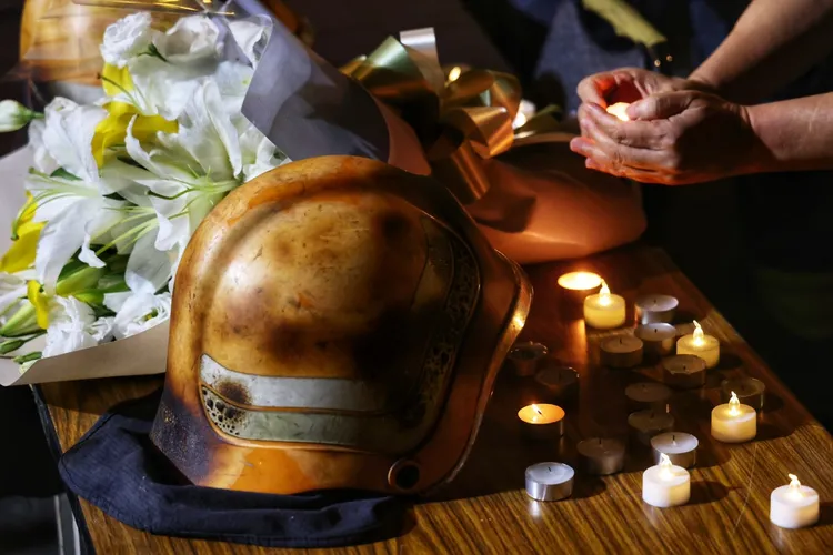 參與晚會的民眾將蠟燭擺在象徵4位殉職消防員的消防帽旁，場面哀戚。林林攝