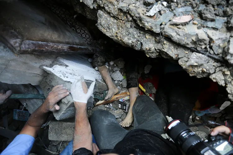 巴勒斯坦民眾從被炸毀的廢墟中搶救兒童。美聯社