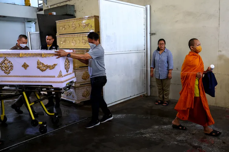 警方移動裝有死者的棺木，一旁有僧人。路透社