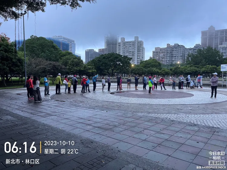 雖然飄著細雨，民眾一早6點多就來社區運動公園排隊，等著升旗。服務處提供