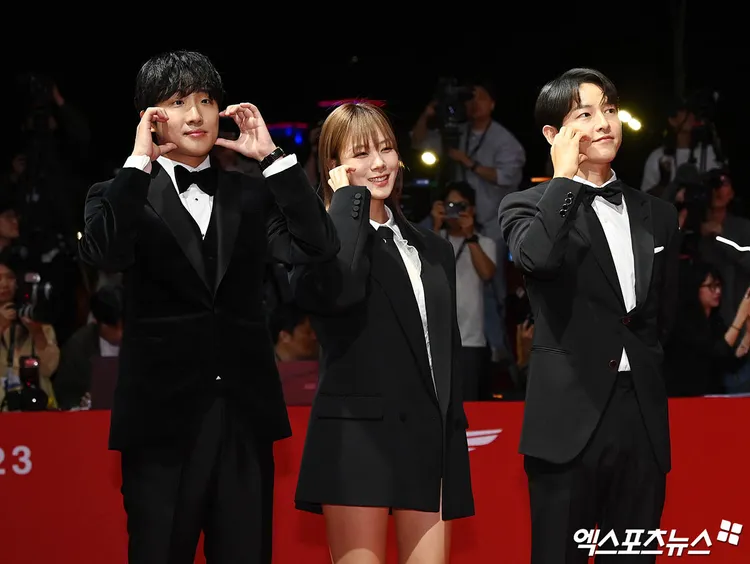 宋仲基（右）率領《禍亂：地下秩序》演員比臉頰愛心。翻攝xportsnews