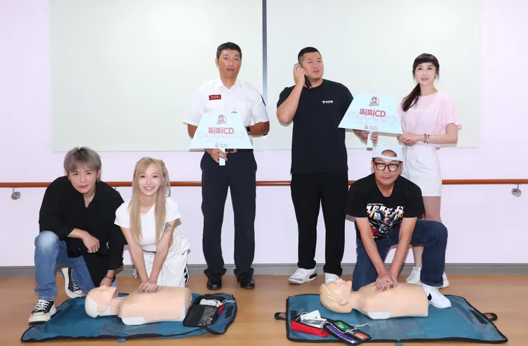 藝人金志遙（前排左起）、嵐芯語、錢小豪、消防員（後排左起）、草爺、蔡允潔等，示範施作心肺復甦術 （CPR+AED）。紅心字會提供