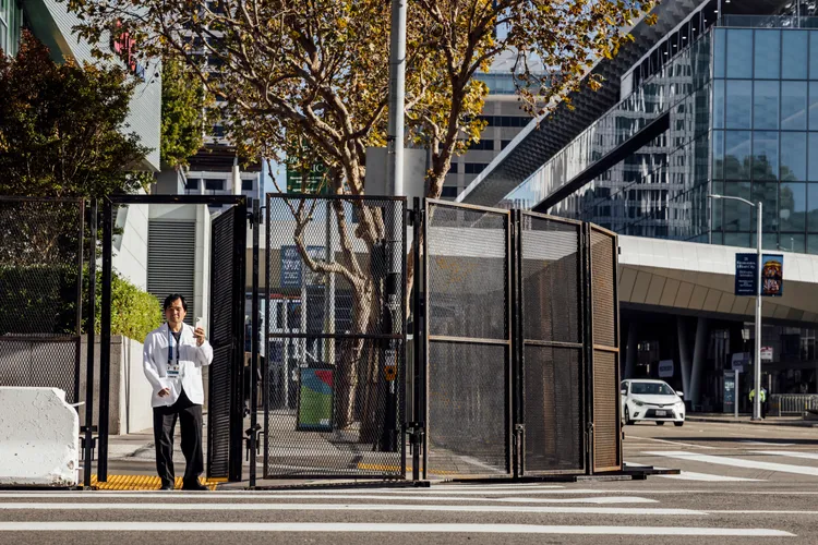 一名工作人員11日站在APEC場館「摩斯康尼中心」外架設的圍欄。美聯社