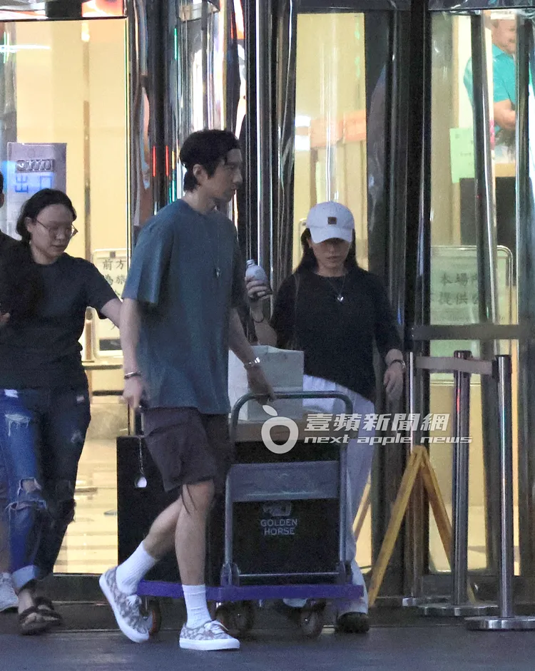 傅孟柏（中）與女友安安推著印有金馬Logo的大禮包走出大樓。特勤中心攝