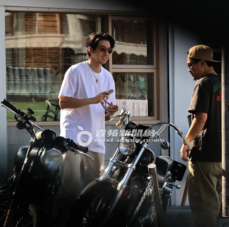 友人拿出單眼相機把玩，熱愛攝影的傅孟柏（左）也跟著一起研究。特勤中心攝