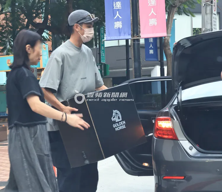 曹佑寧在助理幫忙下，將金馬獎禮箱，搬上多元化計程車。特勤中心攝