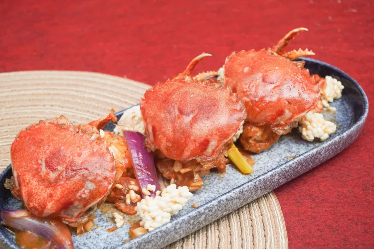 長榮鳳凰秋蟹季可品嚐到「新加坡辣椒蟹」，選用宜蘭在地漁港的牛蹄蟹加入番茄及辣椒一起爆炒，起鍋盛盤周圍放上鍋巴，可以沾著醬汁享用。業者提供