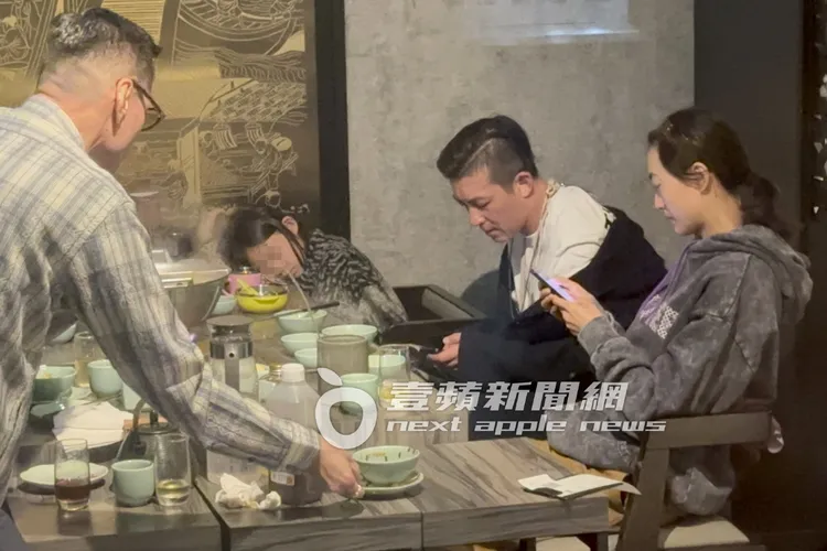 抽完菸，陳冠希走回餐廳穿外套，跟老婆一起滑手機。特勤中心攝