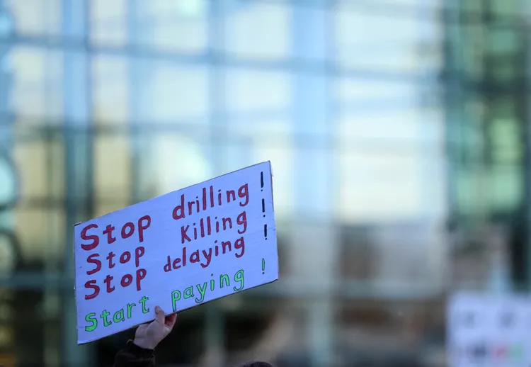 英國有倡議人士舉牌「停止鑽油」。路透社。