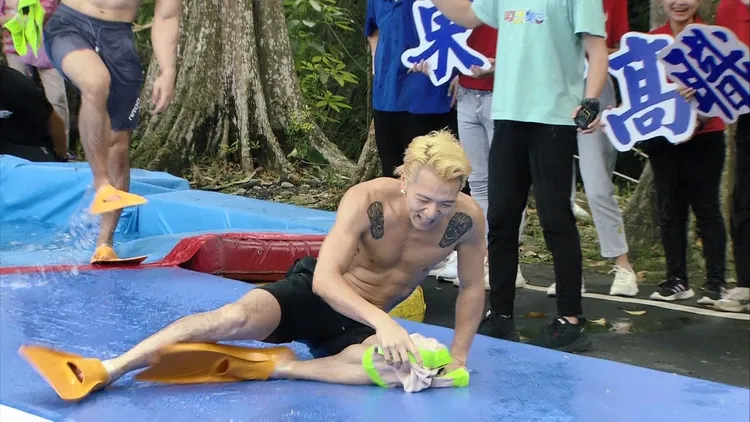 一身肌肉的大飛，穿著蛙鞋，在塑膠跑道奔跑，卻不慎滑倒。民視提供