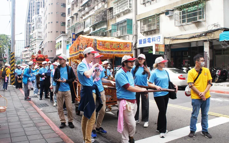 政大副教授高振宏帶領近60位外籍學生，參與北市文山區百年古蹟景美集應廟的繞境活動。政大提供