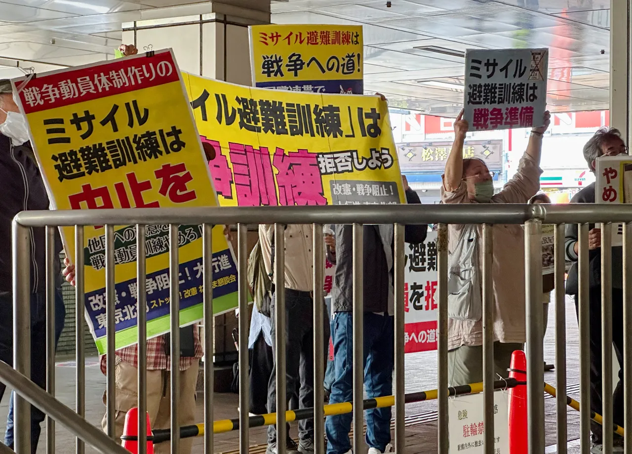 日本反戰人士在防空演習現場舉牌抗議。路透社