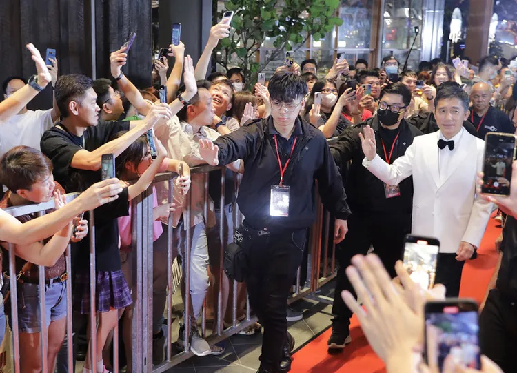 影帝梁朝偉（右白色西裝者）22日在馬來西亞與媒體及粉絲互動，他晚間在吉隆坡商場以走紅地毯方式與粉絲互動，讓粉絲驚呼連連，紛紛拿出手機打卡。中央社
