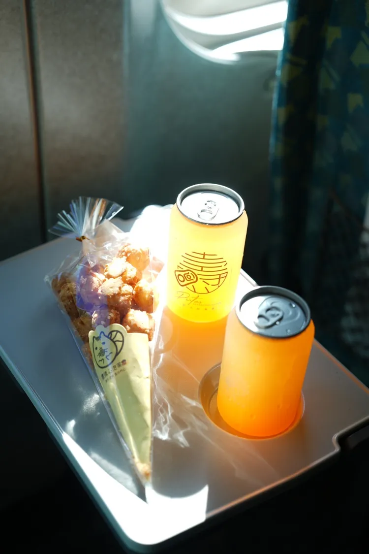 橘色惡魔在高鐵上享用「猜心泡芙」，以及高雄氣泡飲業者準備的「橘色特調」氣泡水。市府提供