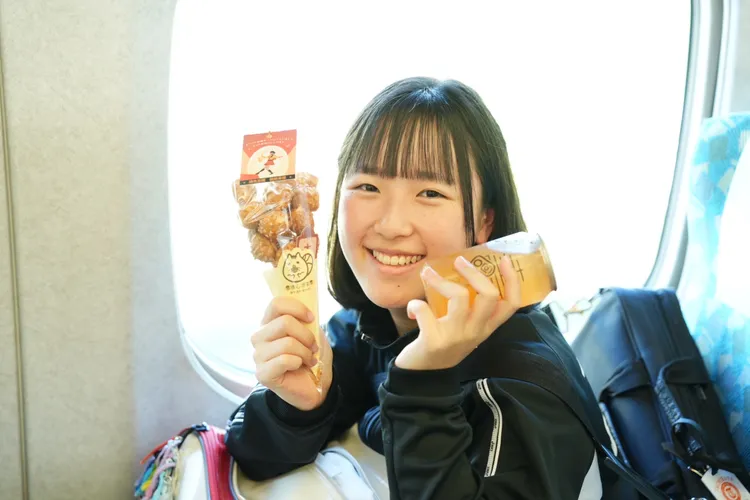 橘色惡魔在高鐵上享用「猜心泡芙」，以及高雄氣泡飲業者準備的「橘色特調」氣泡水。市府提供