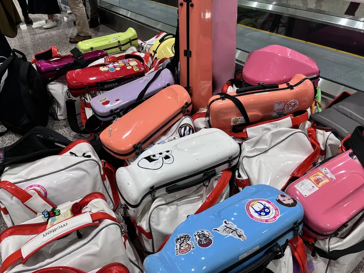 「橘色惡魔」日本京都橘高校吹奏樂部再度訪台，9日晚間搭機抵達桃園國際機場，團員們隨身樂器箱顏色繽紛。 中央社