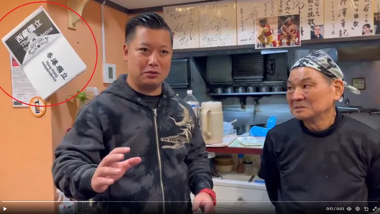 日本網友到該店內採訪老闆表達支持，牆壁上明顯可見辱華標語(紅圈處)。翻攝自推特