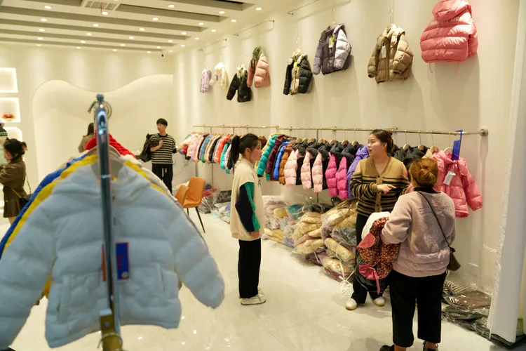 浙江平湖一間服裝店中，顧客選購羽絨衣；2022年平湖羽絨衣出貨量約2億件。新華社