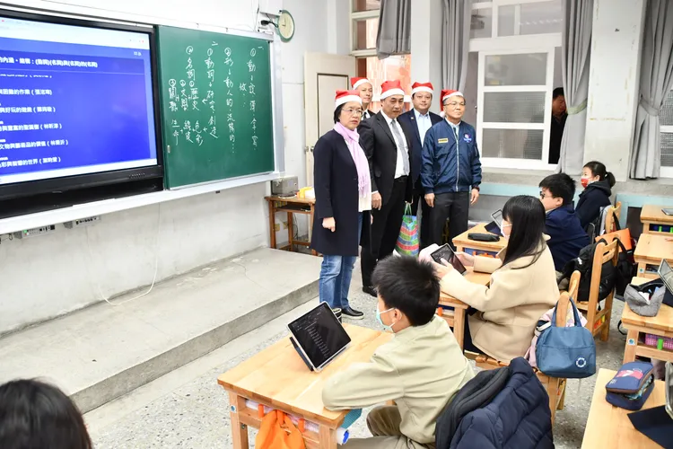 王惠美頭戴聖誕帽，視察學童使用新課桌椅上課的情況。縣府提供