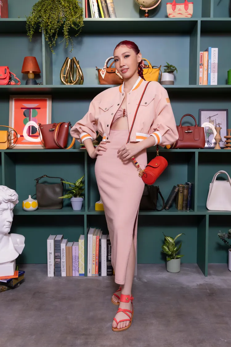 Karencici身穿藕粉色連身洋裝及粉橘色棒球夾克。品牌提供