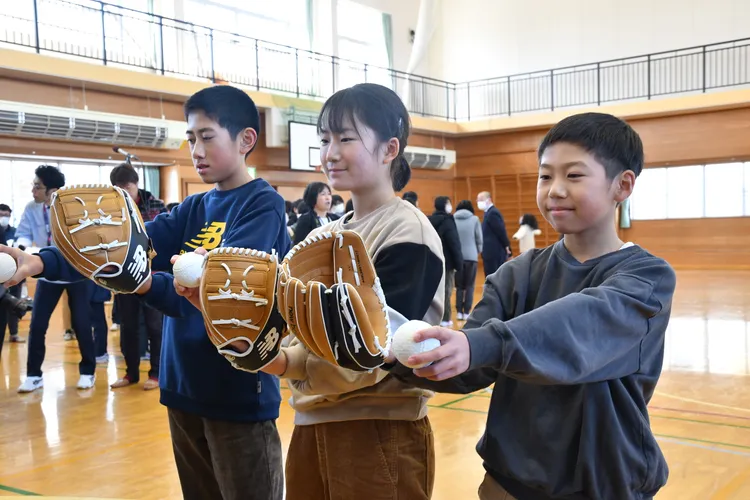 大谷翔平在奧州市的母校舉辦儀式，接受大谷捐贈的棒球手套，學弟妹戴上手套練習接球。翻攝奧州市官方推特
