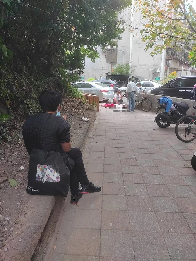 朱男行兇後，坐在路邊抽菸，冷冷望著阿姨倒臥血泊。民眾提供