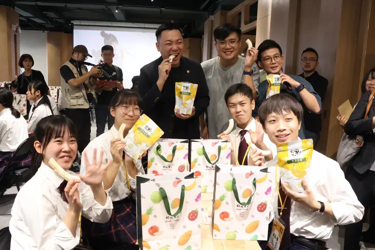 高雄市政府青年局局長張以理 (後排左一)致贈高雄型農研發的「好結果香蕉脆條」，讓學生開心品嚐，留下美好的回憶。青年局提供