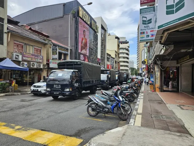 馬來西亞警方21日出動荷槍實彈警力在吉隆坡富都路周邊逮捕非法移工，大批移工四處逃竄。圖為街道上部署的警方車輛與人員。中央社
