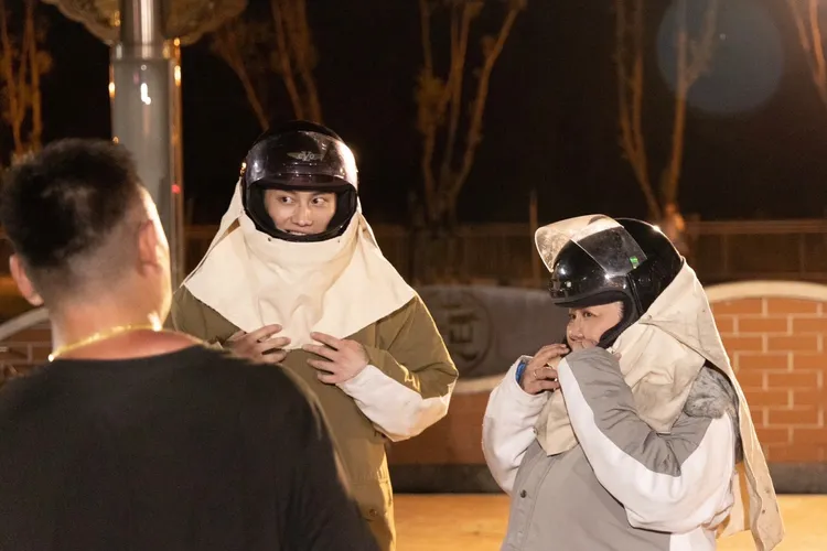 林美秀（右）、范少勳戴安全帽與穿厚外套，體驗被炸蜂炮。民視提供