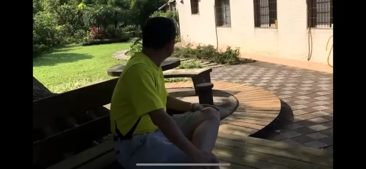 鄉民轉發截圖說，屋旁的樹下有造景乘涼的桌椅。賴清德萬里老家實景影片截圖，翻攝自論壇PTT