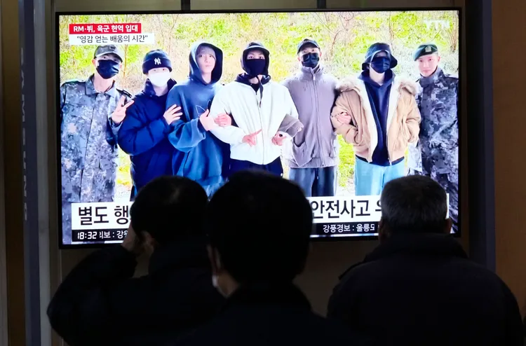 南韓民眾看著電視播放著防彈少年團成員入伍的新聞報導。美聯社