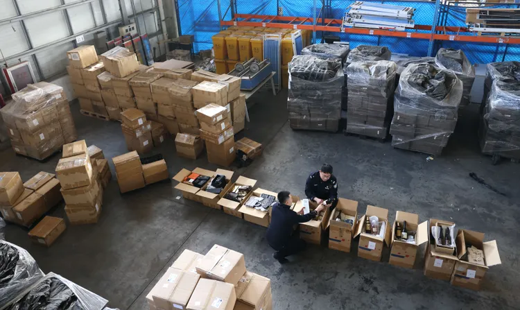 北京海關緝私局所屬首都機場海關緝私分局民警，在首都機場海關南區查驗中心，查驗一批涉偽報品名走私進口的酒類及名牌品。新華社