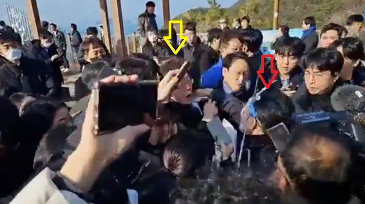 嫌犯（紅箭頭）刺傷李在明（黃箭頭）的頸部。路透社