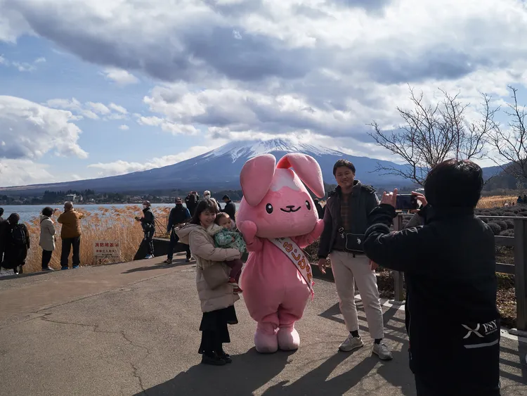 山梨縣河口湖畔的遊客，與吉祥物、富士山合影。新華社