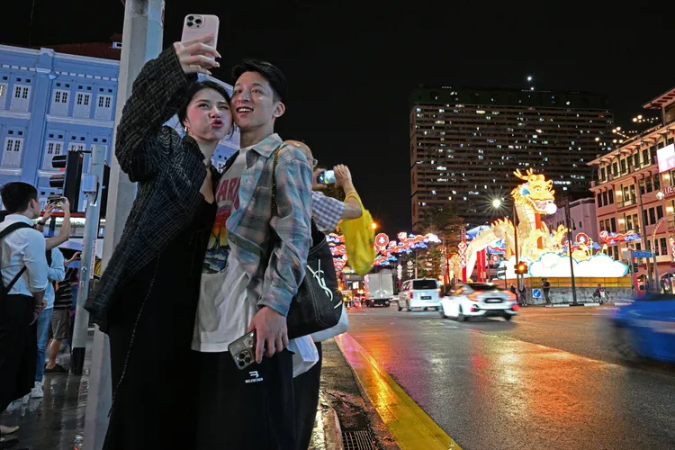 新加坡牛車水龍年燈飾亮燈，民眾與其合影。新華社