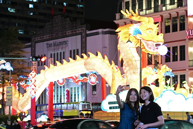 新加坡牛車水龍年燈飾亮燈，民眾與其合影。新華社